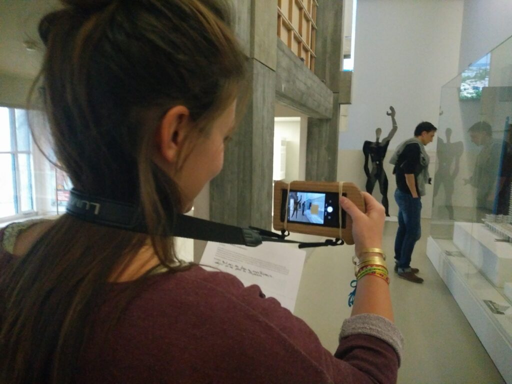 Point de vue subjectif d'une femme utilisant l'appareil photo d'un smartphone en le pointant sur le visiteur d'un musée