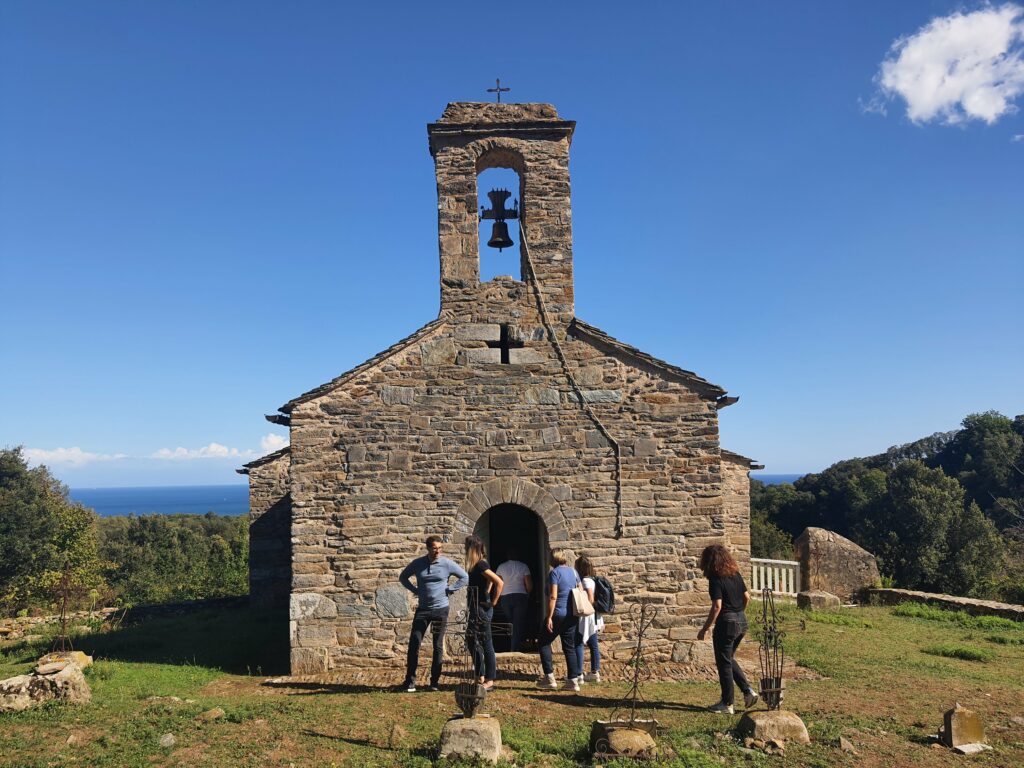 Quelques personnes attendant de pouvoir entrer dans une église isolée sous le ciel bleu de la Corse